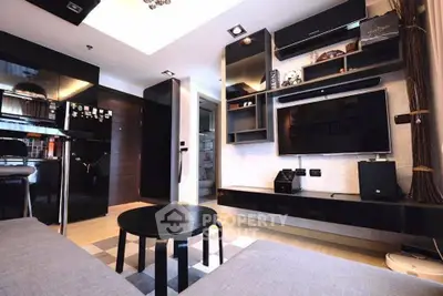Modern living room with sleek black furniture and wall-mounted TV in a stylish apartment.