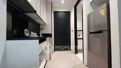 Modern kitchen with sleek cabinetry and stainless steel fridge in a contemporary apartment.