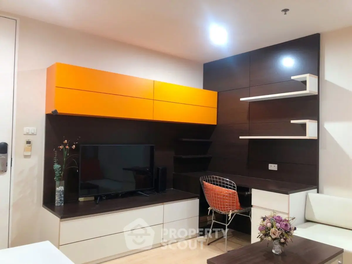 Modern living room with stylish orange cabinets and sleek TV setup.