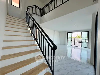 Spacious modern living room with staircase and large windows offering natural light and scenic views.