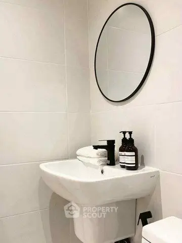 Modern bathroom with sleek sink and round mirror, minimalist design.