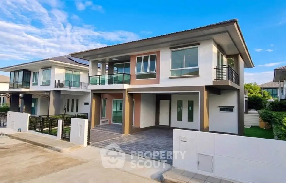 Modern two-story house with large windows and balcony in a suburban neighborhood.