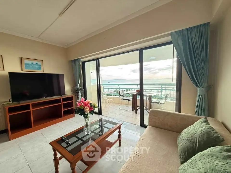 Spacious living room with ocean view balcony, modern furniture, and large TV.