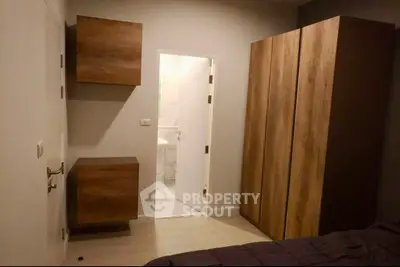 Modern bedroom with wooden wardrobe and bathroom access, ideal for urban living.