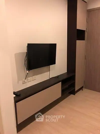 Modern living room with mounted TV and sleek storage unit in a stylish apartment.