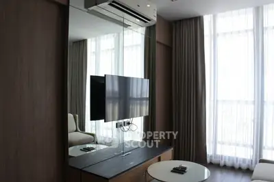 Modern living room with large windows, wall-mounted TV, and sleek furniture design.