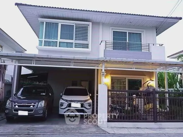 Modern two-story house with carport and balcony in a suburban neighborhood.