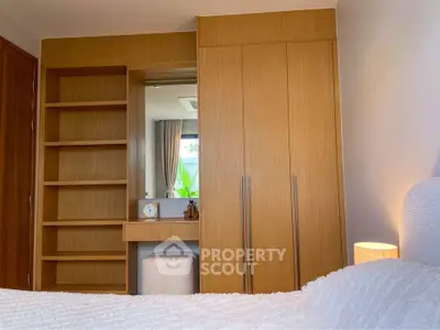 Cozy bedroom with built-in wooden wardrobe and shelves, featuring a serene ambiance and natural light.