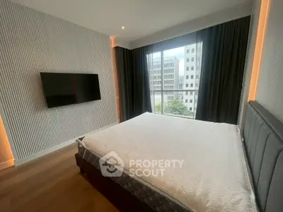 Modern bedroom with large window and city view, featuring a wall-mounted TV and stylish decor.