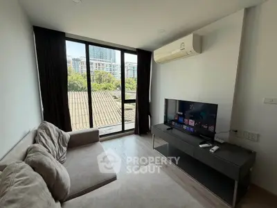 Modern living room with large window and city view, featuring a cozy sofa and flat-screen TV.