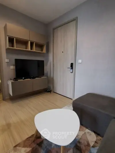 Modern living room with stylish furniture and TV setup, featuring a cozy atmosphere.