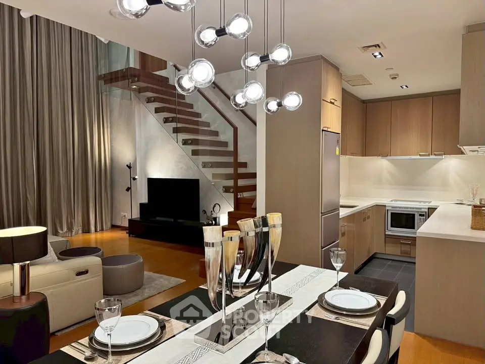 Modern open-plan living room and kitchen with stylish lighting and wooden staircase