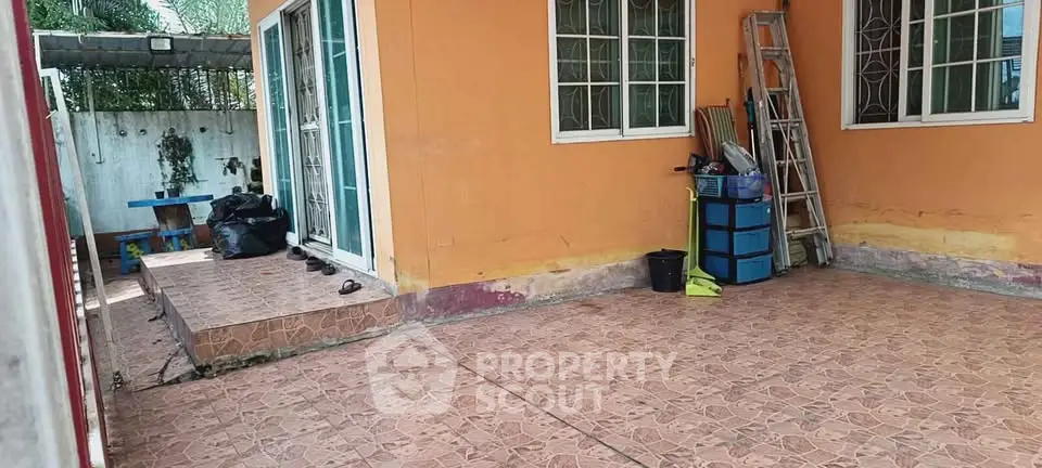 Charming outdoor patio area with tiled flooring and vibrant orange walls, perfect for relaxation and gatherings.