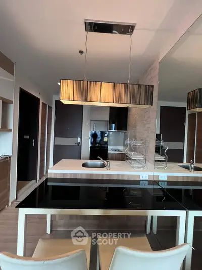 Modern kitchen with sleek design, featuring a stylish pendant light, black countertops, and integrated appliances.