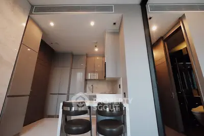 Modern kitchen with sleek cabinetry and stylish bar stools in a contemporary apartment.