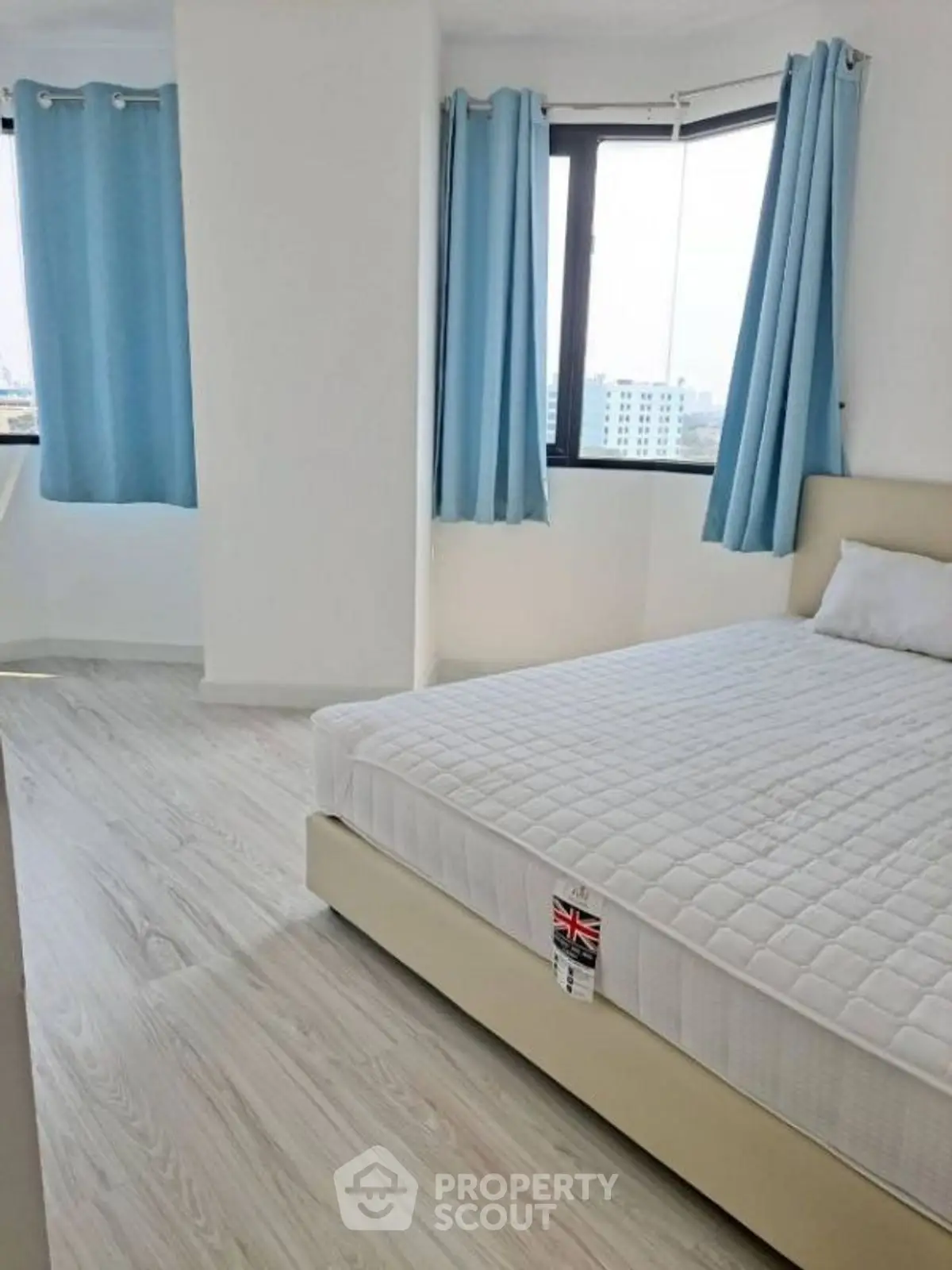 Bright bedroom with large windows and modern decor in a high-rise apartment.