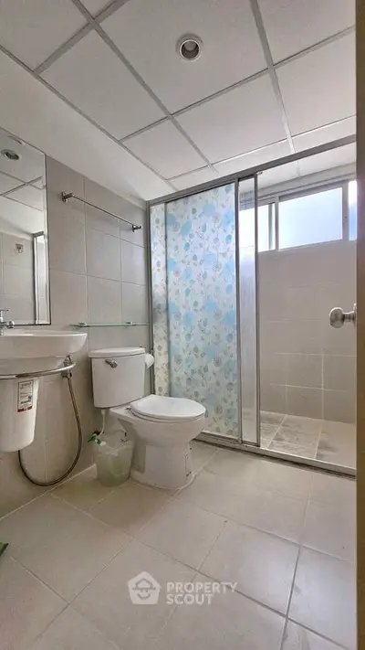 Modern bathroom with glass shower and tiled floor in a bright setting.