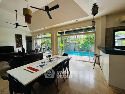 Spacious open-plan living and dining area with pool view, featuring modern decor and ample natural light.