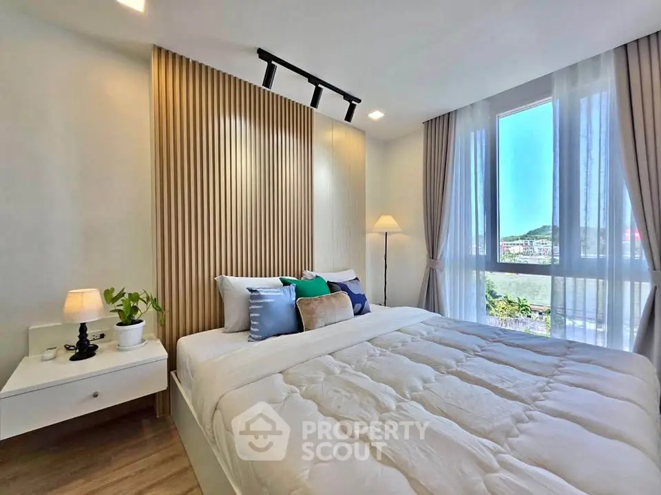 Modern bedroom with stylish decor and large window offering scenic views