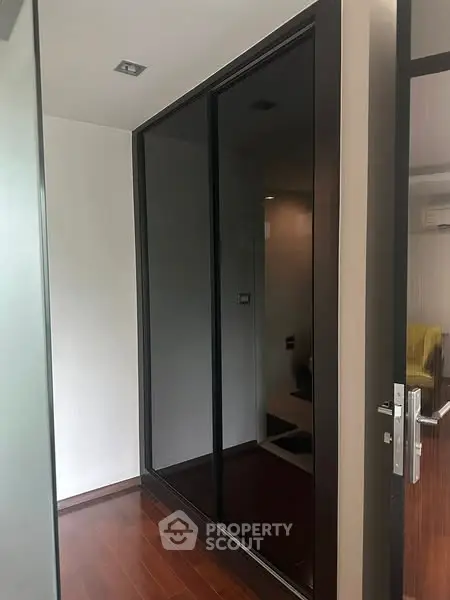 Modern hallway with sleek dark glass wardrobe and wooden flooring