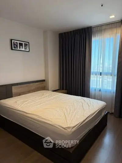 Spacious bedroom with large window and modern decor, perfect for relaxation and comfort.