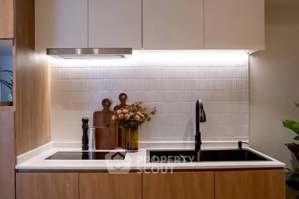 Modern kitchen with sleek cabinetry and elegant lighting, featuring a stylish black faucet and induction cooktop.