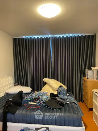 Cozy bedroom with modern decor and ample natural light through large windows.