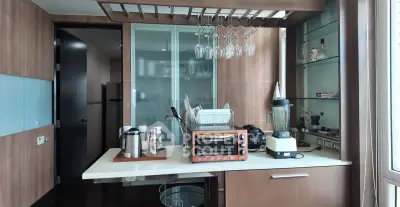 Modern kitchen with wooden cabinets, glass rack, and appliances including blender and oven.