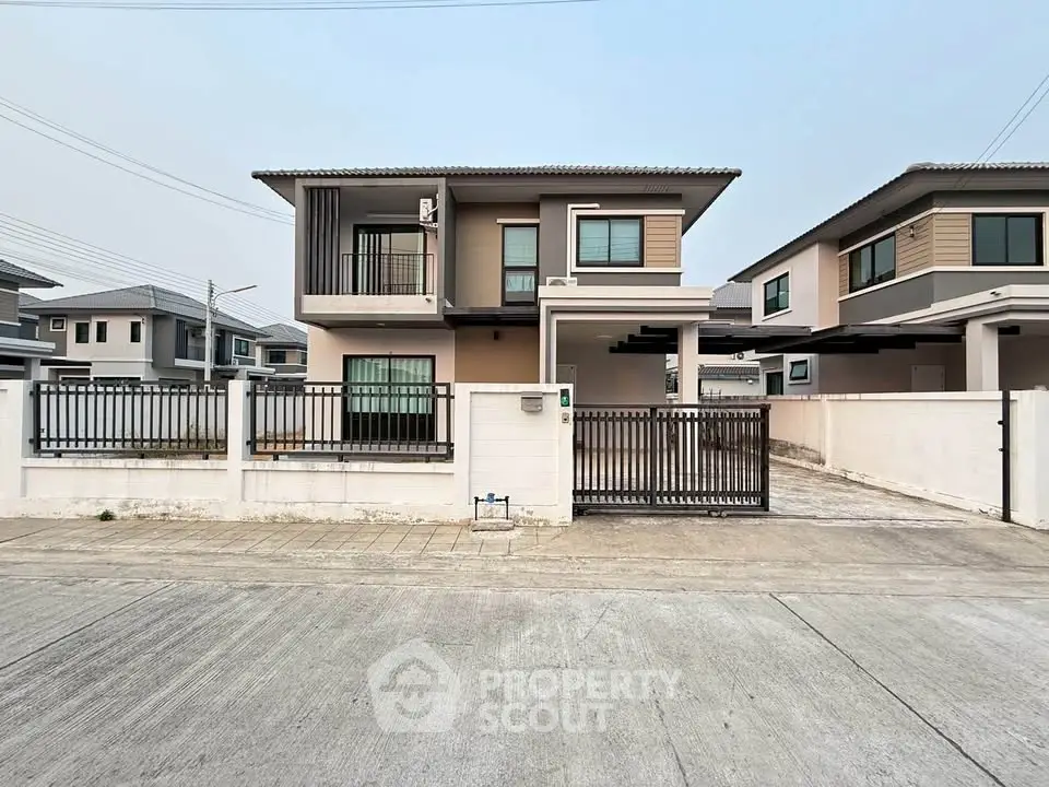 Modern two-story house with gated driveway and contemporary design.