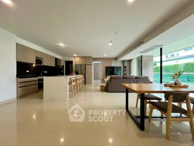 Spacious open-plan living room with modern kitchen and dining area, featuring sleek design and ample natural light.