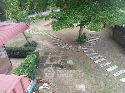 Charming backyard garden with a creative stepping stone path, surrounded by lush greenery and mature trees, offering a serene outdoor retreat.
