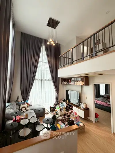 Spacious living room with high ceilings and mezzanine, featuring modern decor and ample natural light.