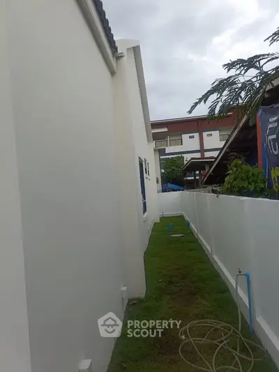 Narrow side yard with grass and white fence beside modern house exterior.