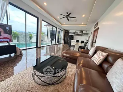 Luxurious living room with pool view, modern furniture, and open kitchen layout