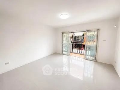 Spacious living room with large windows and balcony access, offering ample natural light and a serene view.