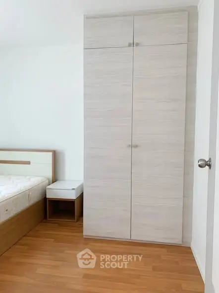 Modern bedroom with sleek wooden flooring and built-in wardrobe