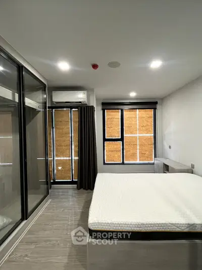 Modern bedroom with sleek design, featuring large windows and ample natural light.