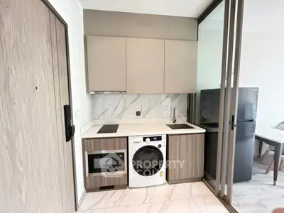 Modern kitchen with washing machine, microwave, and sleek cabinetry