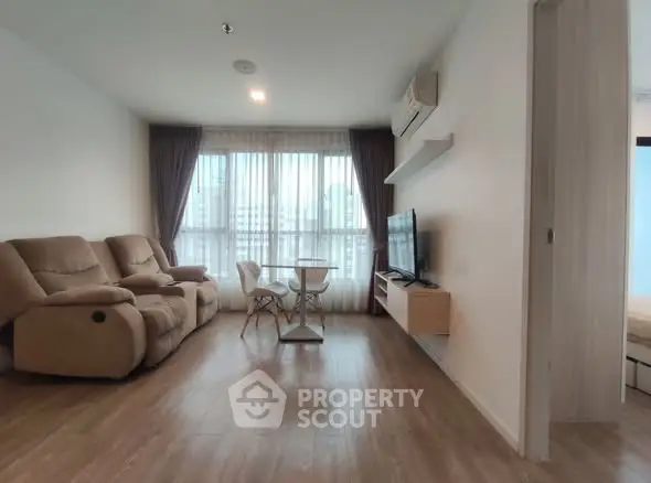 Modern living room with cozy seating and large window in a stylish apartment.