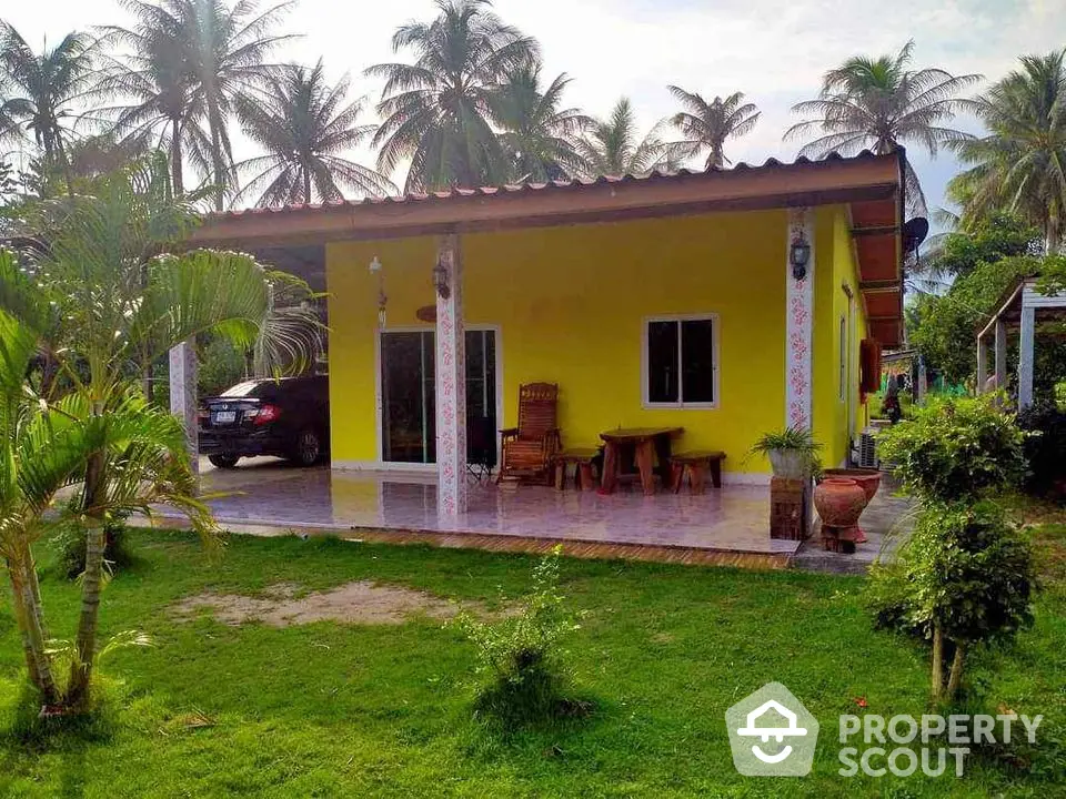 Charming tropical yellow house with lush garden and palm trees