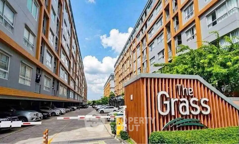 Modern apartment complex with ample parking and lush greenery at The Grass.