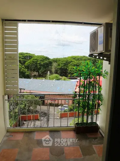 Charming balcony with lush green view and air conditioning unit, perfect for relaxation.