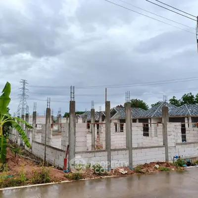 Under-construction residential building with concrete pillars and brick walls on a cloudy day.