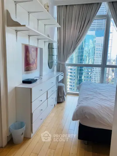 Bright bedroom with city view, featuring modern furniture and large windows for natural light.