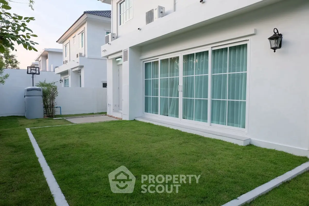 Modern white house with lush green lawn and sliding glass doors