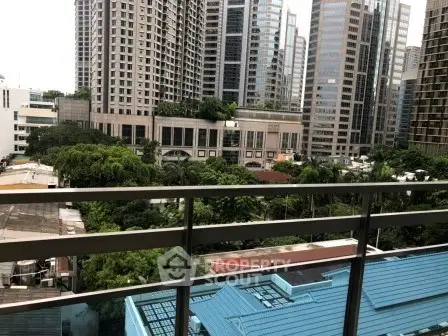 Stunning urban view from a high-rise balcony overlooking lush greenery and modern skyscrapers.