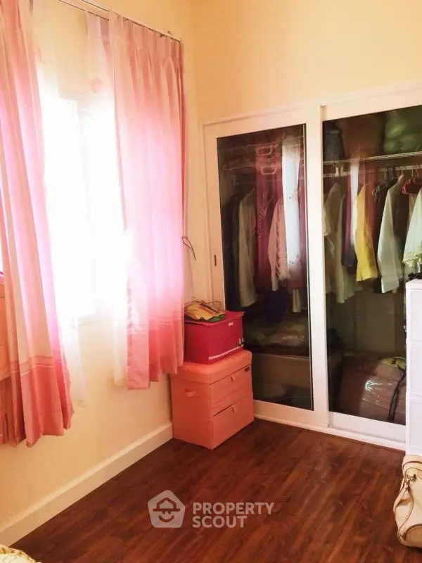 Charming bedroom with pink curtains and mirrored wardrobe, perfect for cozy living.