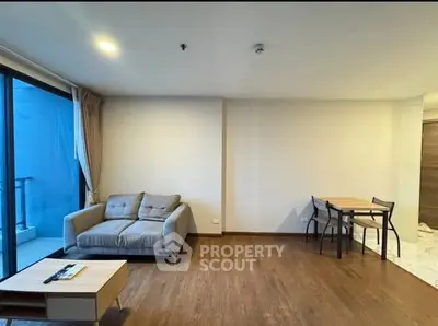 Modern living room with cozy sofa and dining area, featuring wooden flooring and natural light.