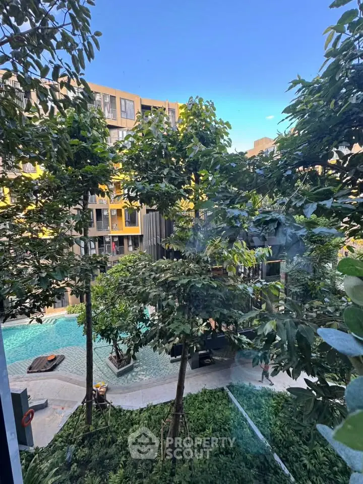 Luxurious apartment complex with lush greenery and inviting pool view.