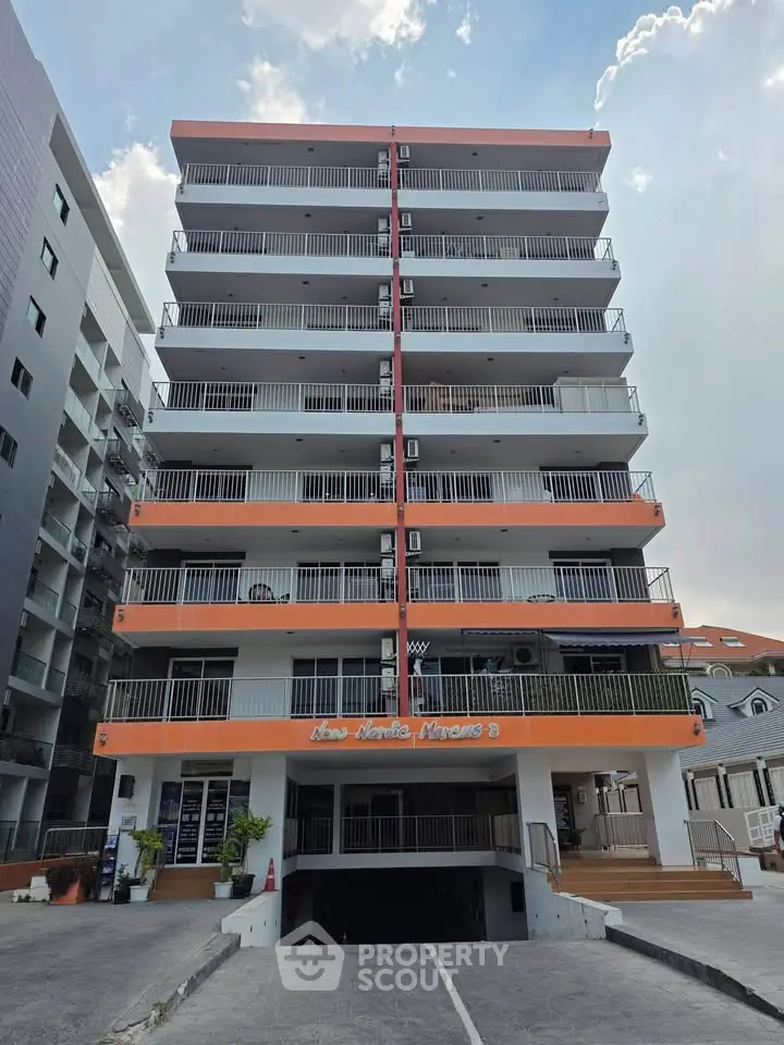 Modern multi-story apartment building with balconies and parking entrance, ideal for urban living.